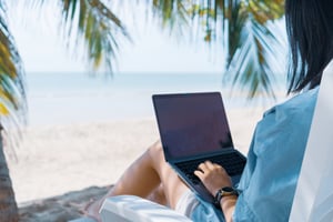 Frau mit Laptop und Smartphone zu arbeitet im Urlaub